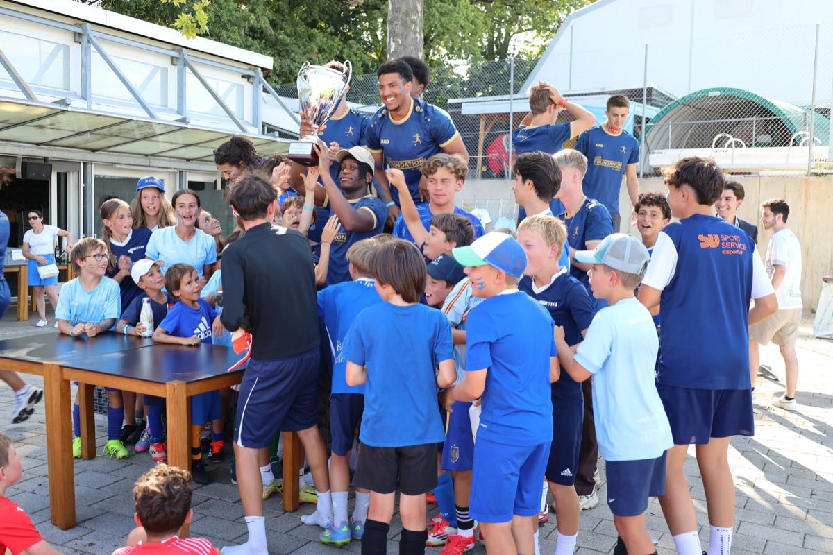 Les enfants rassemblés autour du trophée soulevé, à la fin du camp 2025
